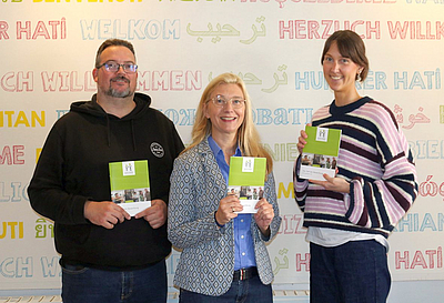 Drei Personen halten das neue 1x1 hoch. 