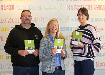 Drei Personen halten das neue 1x1 hoch. 