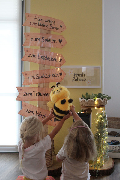 Zwei Kinder halten eine Kuscheltierbiene in die Luft