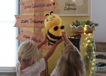 Zwei Kinder halten eine Kuscheltierbiene in die Luft