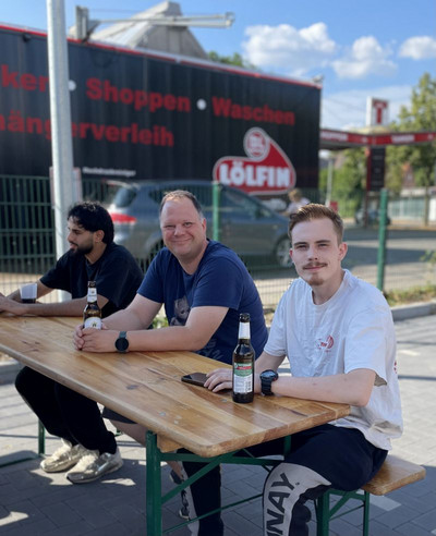 Drei Personen sitzen am Tisch