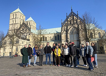 Eine Gruppe aus sechzehn Personen steht vor dem St. Paulus Dom in Münster