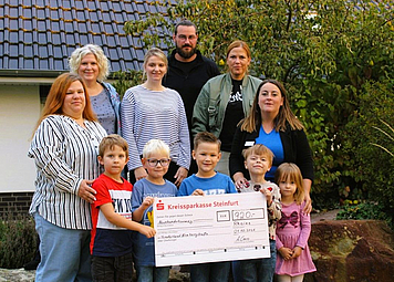 Kinder halten einen Check in der Hand und die Erzieher stehen dahinter 