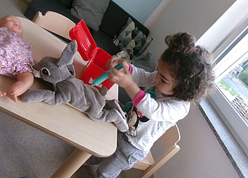 Ein Kind an einem Tisch auf dem Kuscheltierhase liegt un mit einer Spielzeug spritze in der Hand verarztet wird
