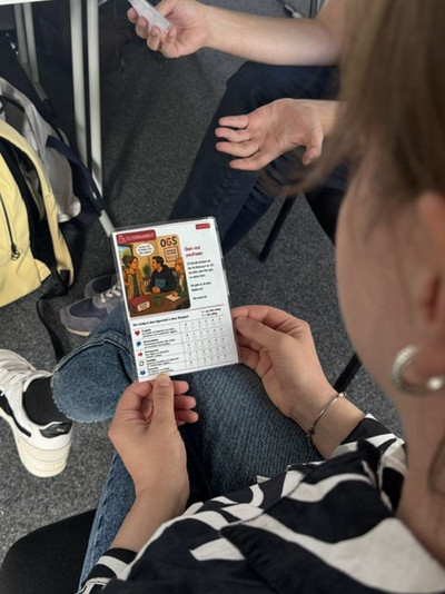 Es ist eine Spielkarte zu sehen, welche in der Hand gehalten wird 