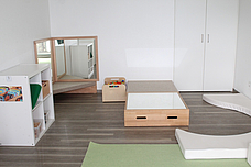 Ein heller Nebenraum, mit einem weißen regal und Potesten, sowie ein Spiegel in der Ecke 