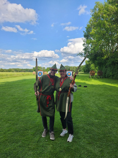 Zewi Personen im Robin Hood Kostüm freuen sich auf einer Wiese. 