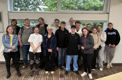 Auf dem Gruppenfoto sind 17 lächelnde Personen zu sehen. Es handelt sich um die neuen Auszubildenden von Lernen fördern e.V. am Standort Steinfurt für das Jahr 2025. 