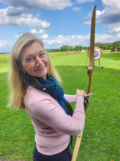 Eine Frau posiert beim Bogen schießen. 