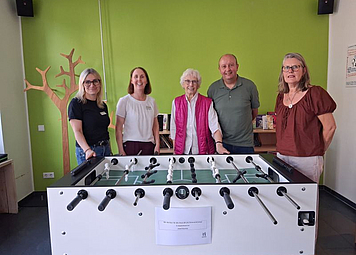 5 Personen stehen hinter einem modernen Kicker