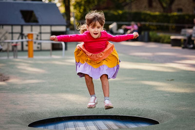 Wir sehen ein Mädchen auf einen Trampolin hüpfen.