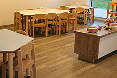 Die kleine Küche. In der Mitte Tische mit Stühlen, davor das Kinderbuffet.