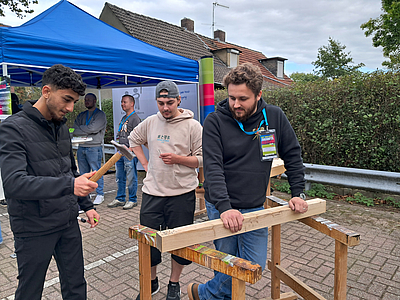 mehrere Personen arbeiten an einer Holzwerkbank