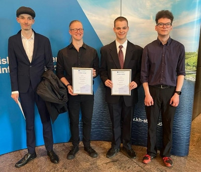 Auf dem Foto sind vier Absolventen zu sehen. Die zwei in der Mitte stehenden Personen halten ihre Auszeichnung als Prüfungsbeste in den Händen. Von links betrachtet sieht man auf dem Foto David Piesik, Nils Zimny, René Sack und Pascal Esser. 