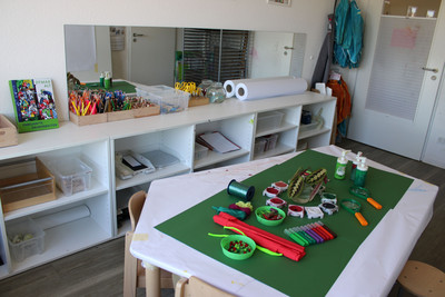 Das Atelier. Ein vorbereiteter Tisch  mit grünen und roten Elementen.