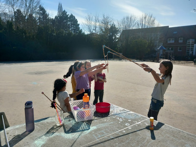 Eine kleine gruppe Mädchen im Pausenhof der Schule die mit Seifenblasen spielen.