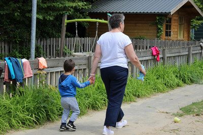 Auf dem Foto ist ein Kindergartenkind und seine Oma von hinten auf dem Spielplatz zu sehen