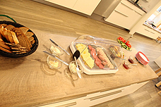 Unser Kinderbuffet aufgebaut. Brot, Aufschnitt, Aufstrich, sowie Obst und Gemüse und ganz zu Anfang viele Teller aufeinander gestapelt