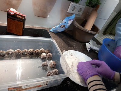 Hände bereiten Pralinen zu. 