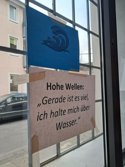 Es ist ein Plakat zu sehen, auf dem steht Hohe Wellen Gerade ist es zu viel, ich halte mich über Wasser