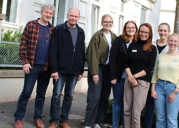 12 Menschen vor einem Gebäude