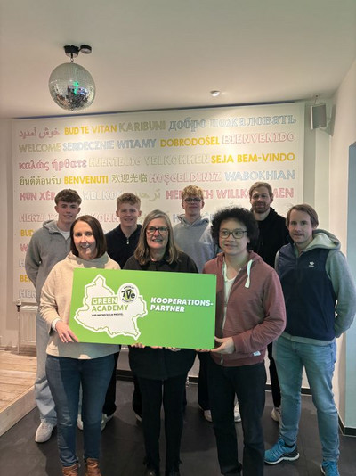 Ein Gruppenfoto vor einer bunten Tapete. Die vordersten Personen halten ein Schild mit der Aufschrift: "Kooperationspartner".