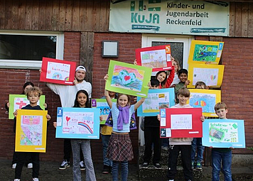 Kinder zeigen ihre selbst gestalteten Bilder zu den Kinderrechten.