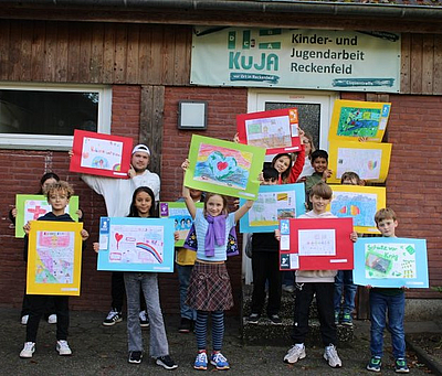 Kinder zeigen ihre selbst gestalteten Bilder zu den Kinderrechten.