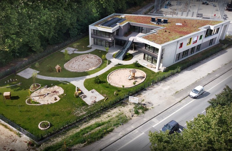 Luftaufnahme eines stylischen Kindergartengebäudes mit Spielplatz